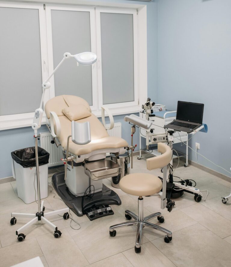 A clean and modern medical clinic examination room with equipment and chairs.